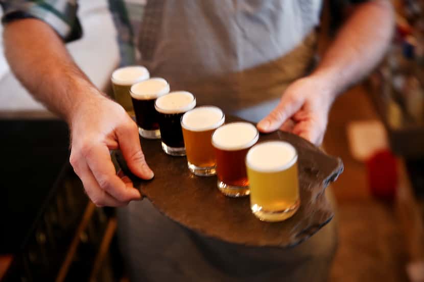 Joshua Dawn, co-owner of Small Brewpub, delivers a flight of beer to patrons inside the Oak...