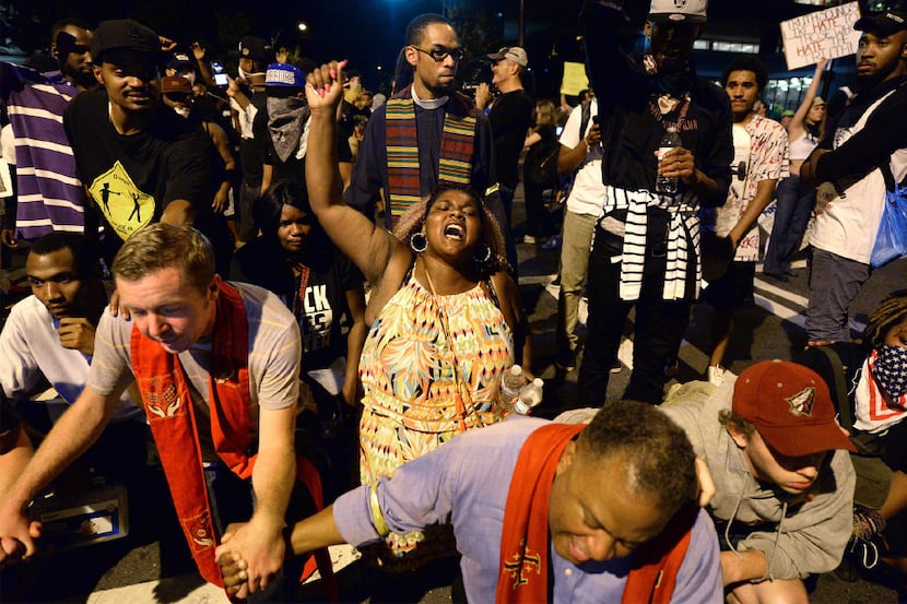 Clergy and protesters pray outside the Charlotte Police Dept. in Charlotte, N.C., after...