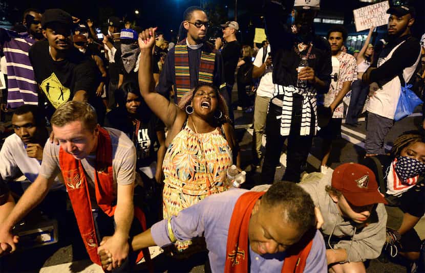 Clergy and protesters pray outside the Charlotte Police Dept. in Charlotte, N.C., after...