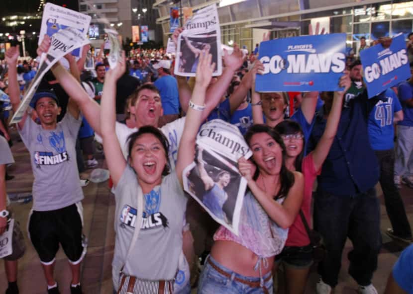 Fans celebrate with editions of the Dallas Morning News outside the arena after the Mavs...