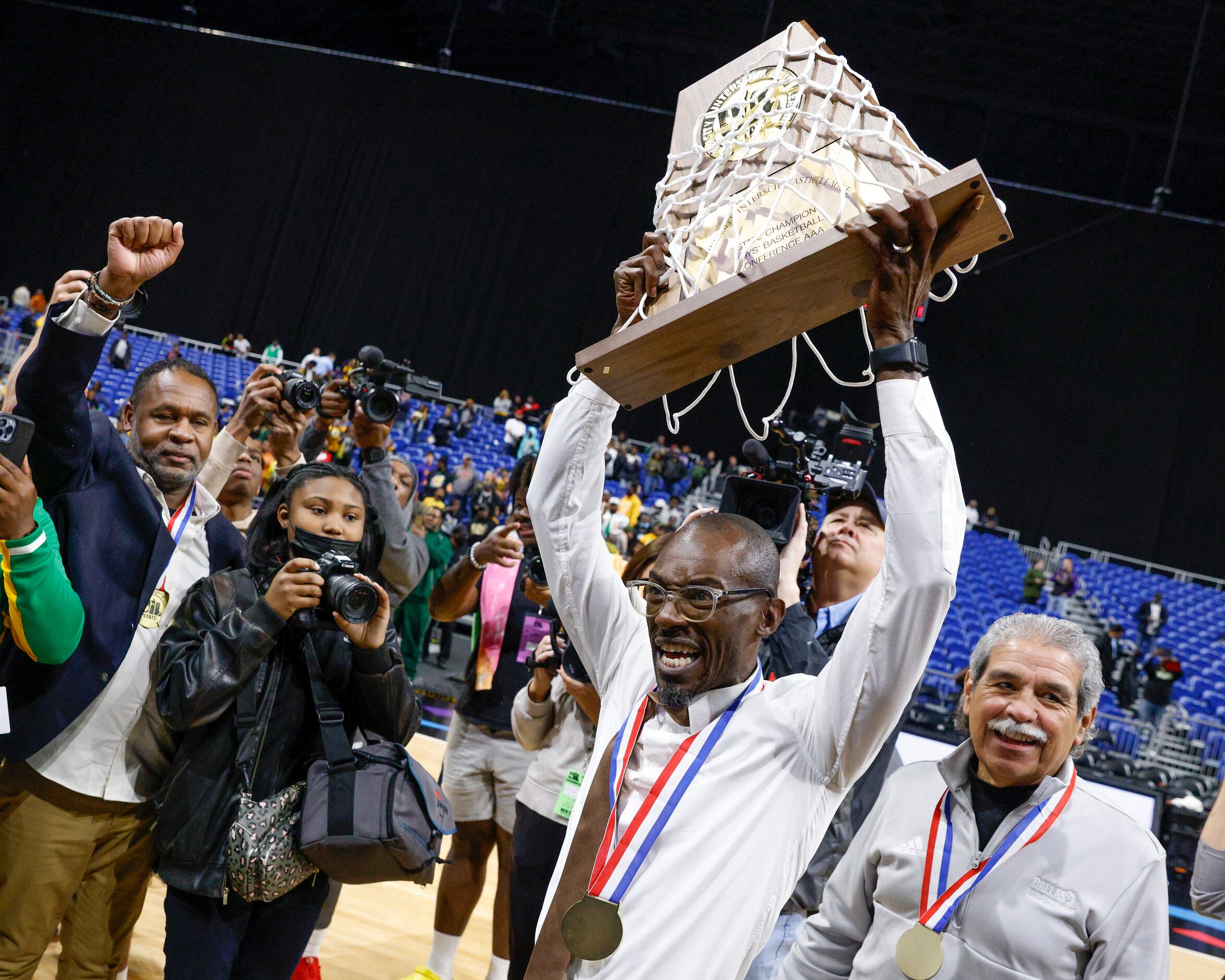Madison head coach Damien Mobley raises the Class 3A state championship trophy alongside...