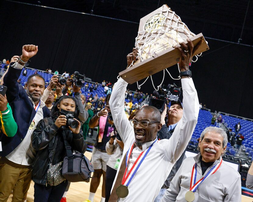 Madison head coach Damien Mobley raises the Class 3A state championship trophy alongside...