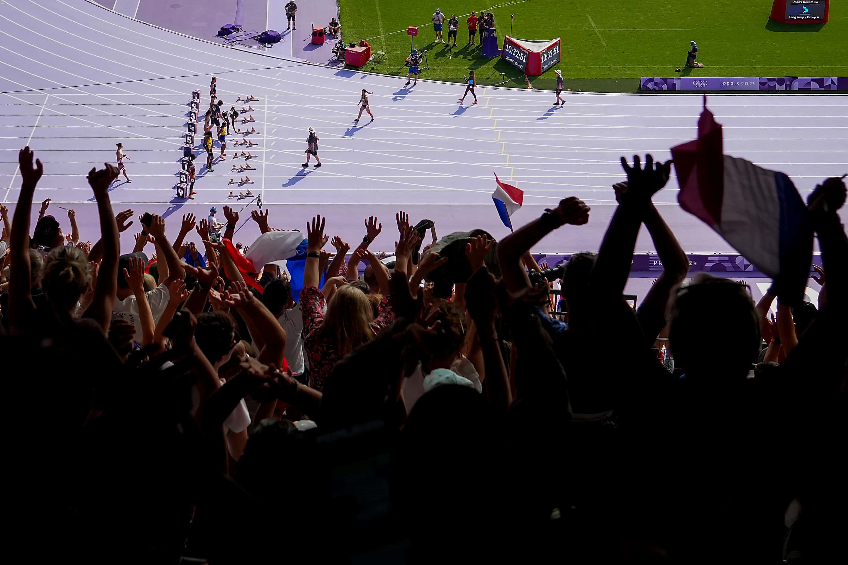 Fans cheer as athletes are announced for a preliminary heat of the women’s 100-meters at the...