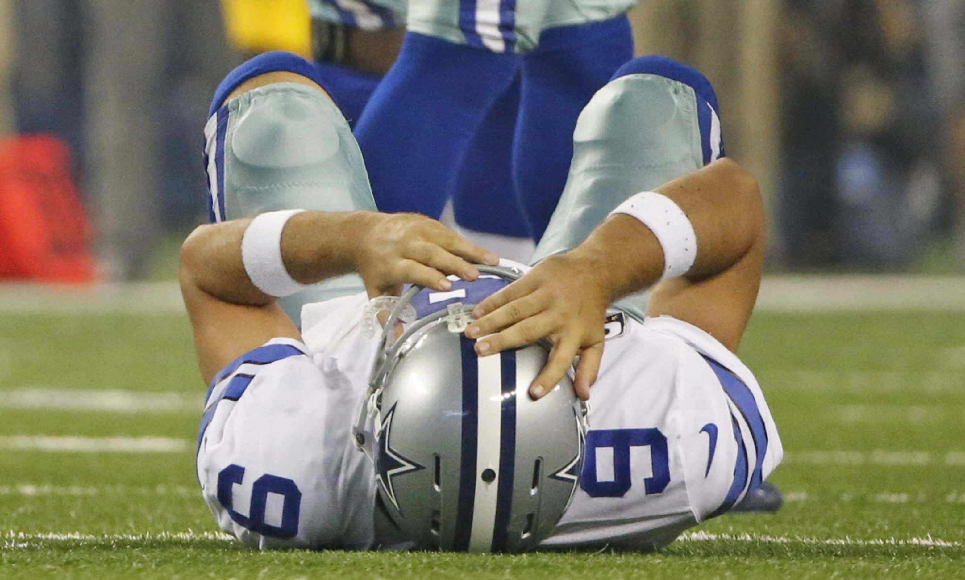 Dallas Cowboys quarterback Tony Romo (9) lies on the ground after being crunched by...