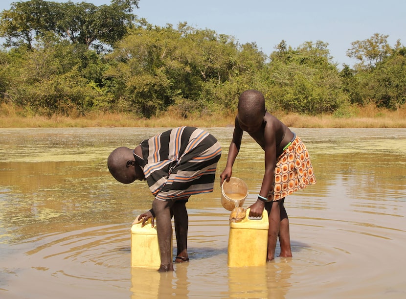 FILE - In this Nov. 4, 2010 photo, children collect drinking water from a pond using filters...