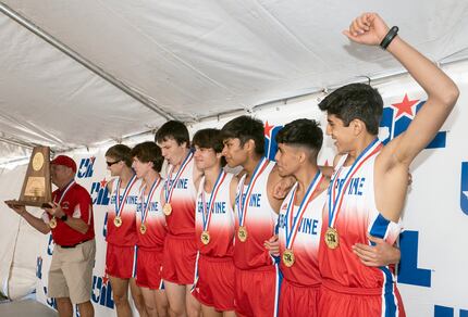 Members of the Grapevine boys 5A cross country team celebrate as coach, Rich Miller,...