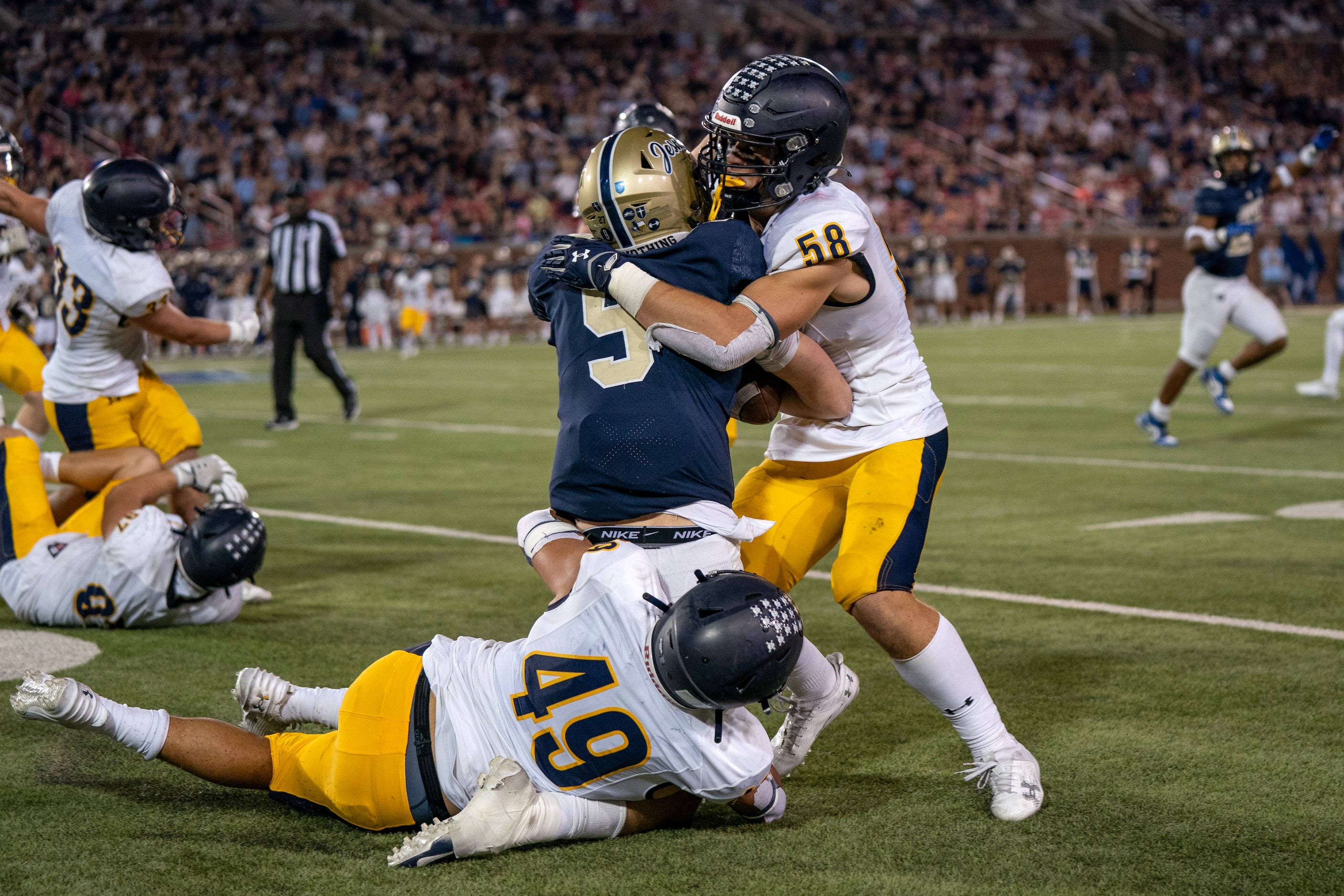 Highland Park junior linebackers Anders Corn (58) and Jack Morse (49) wrap up Jesuit junior...