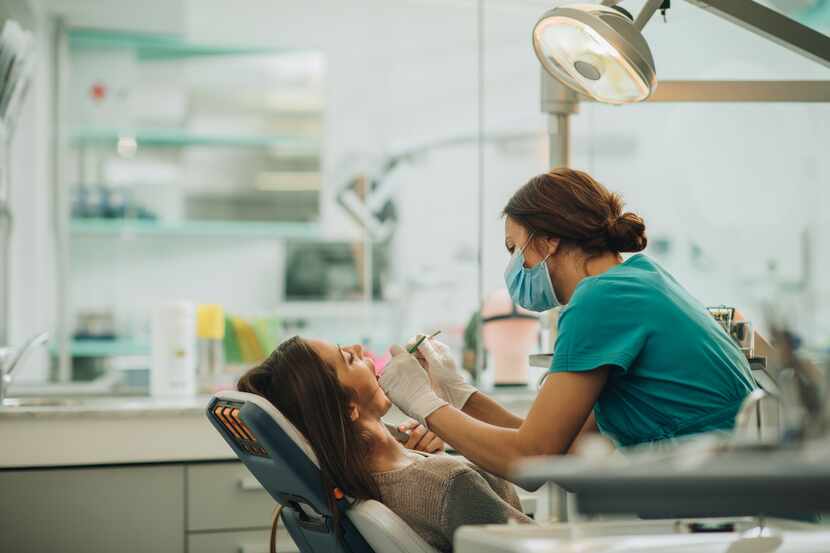 Una mujer recibe atención a su dentadura en un consultorio dental.
