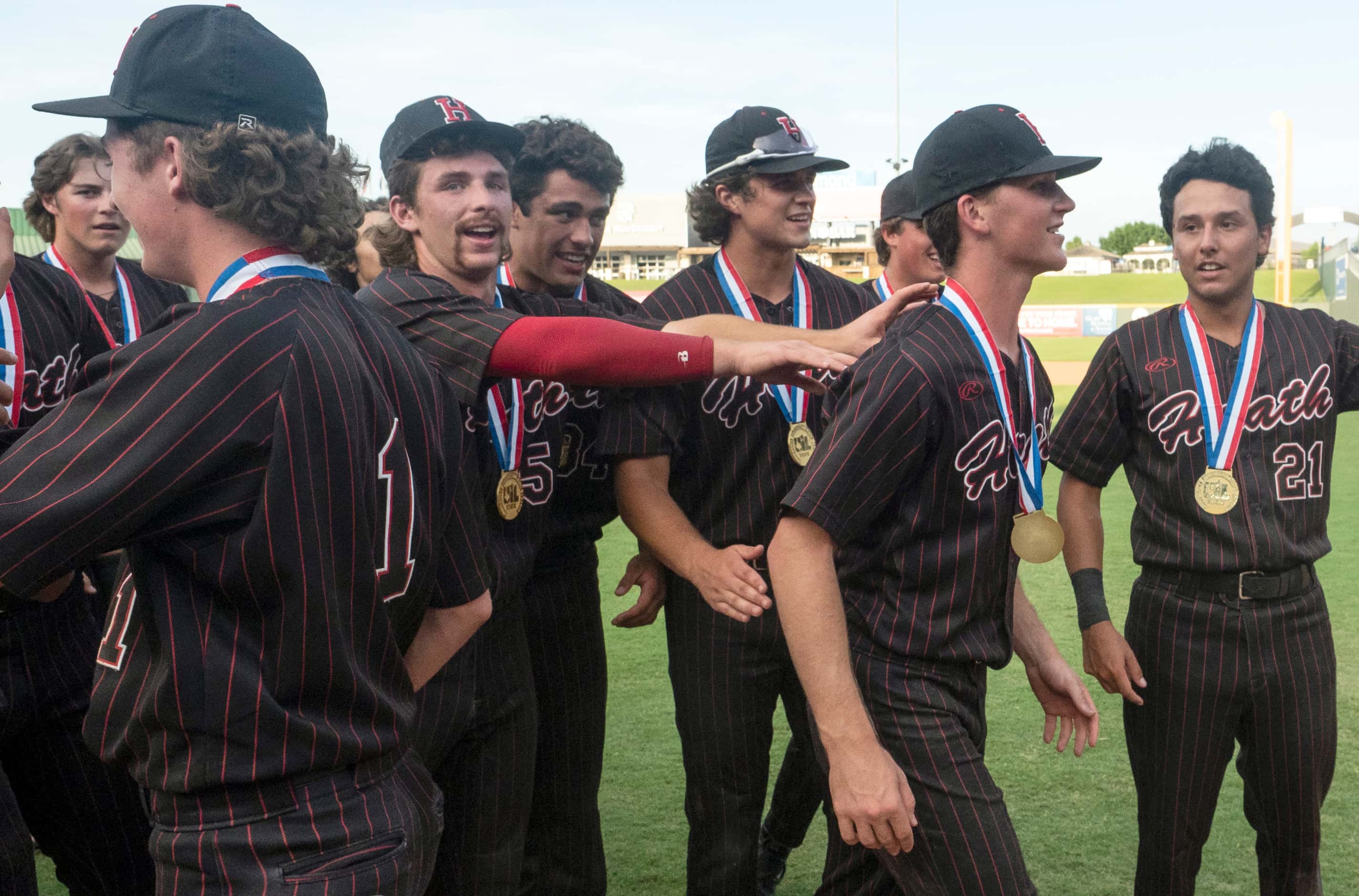 Tournament MVP Rockwall-Heath Caden Fiveash, (16), is pushed by teammates towards home plate...