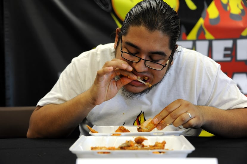 Kevin Gonzalez eats wings by Wing Town at the Taste of Irving Fiery Heat Challenge in...