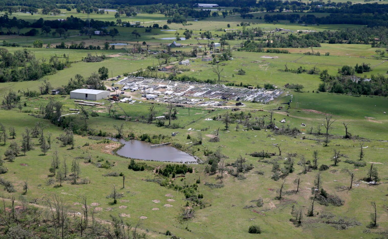 Damaged greenhouses and trees are seen from the air after severe storms including tornadoes...