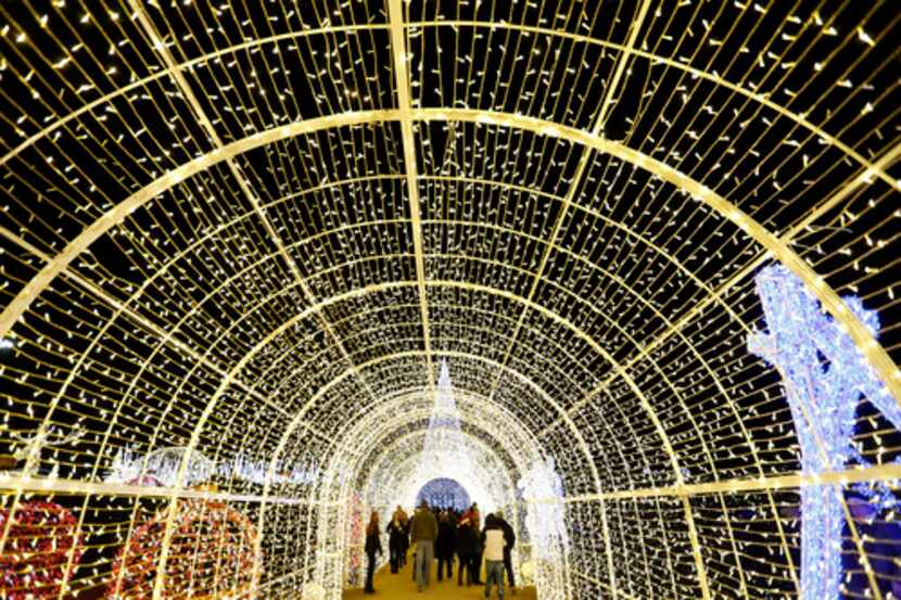 La gente pasa por debajo de un túnel de luces en Enchant: The World’s Largest Christmas...