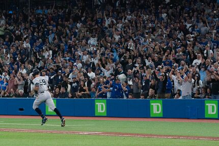 Fans react as New York Yankees' Aaron Judge rounds first base after hitting his 61st home...