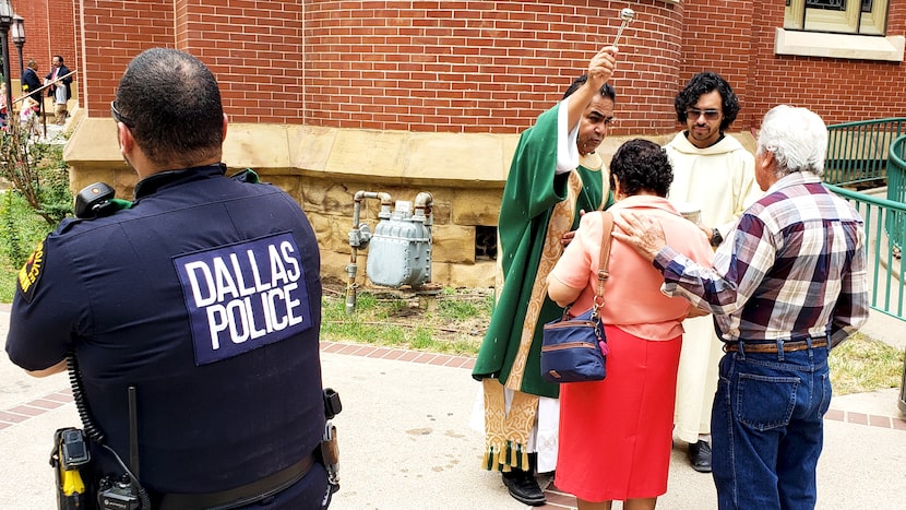 Deacon Roberto Alvarez and Raul Rodriguez bless a couple with holy water Sunday as Dallas...