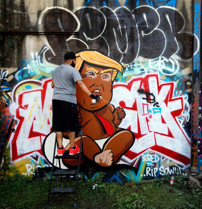 Dallas artist Jeremy Biggers cleared his spray can as he painted a caricature of...