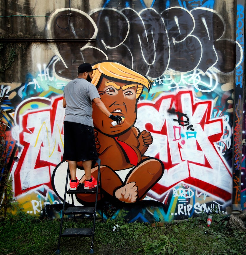 Dallas artist Jeremy Biggers cleared his spray can as he painted a caricature of...