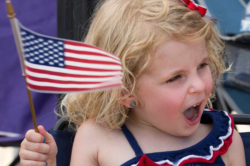 Katie Shearer, 4, of Arlington waves her flag as she watches the Arlington Fourth of July...