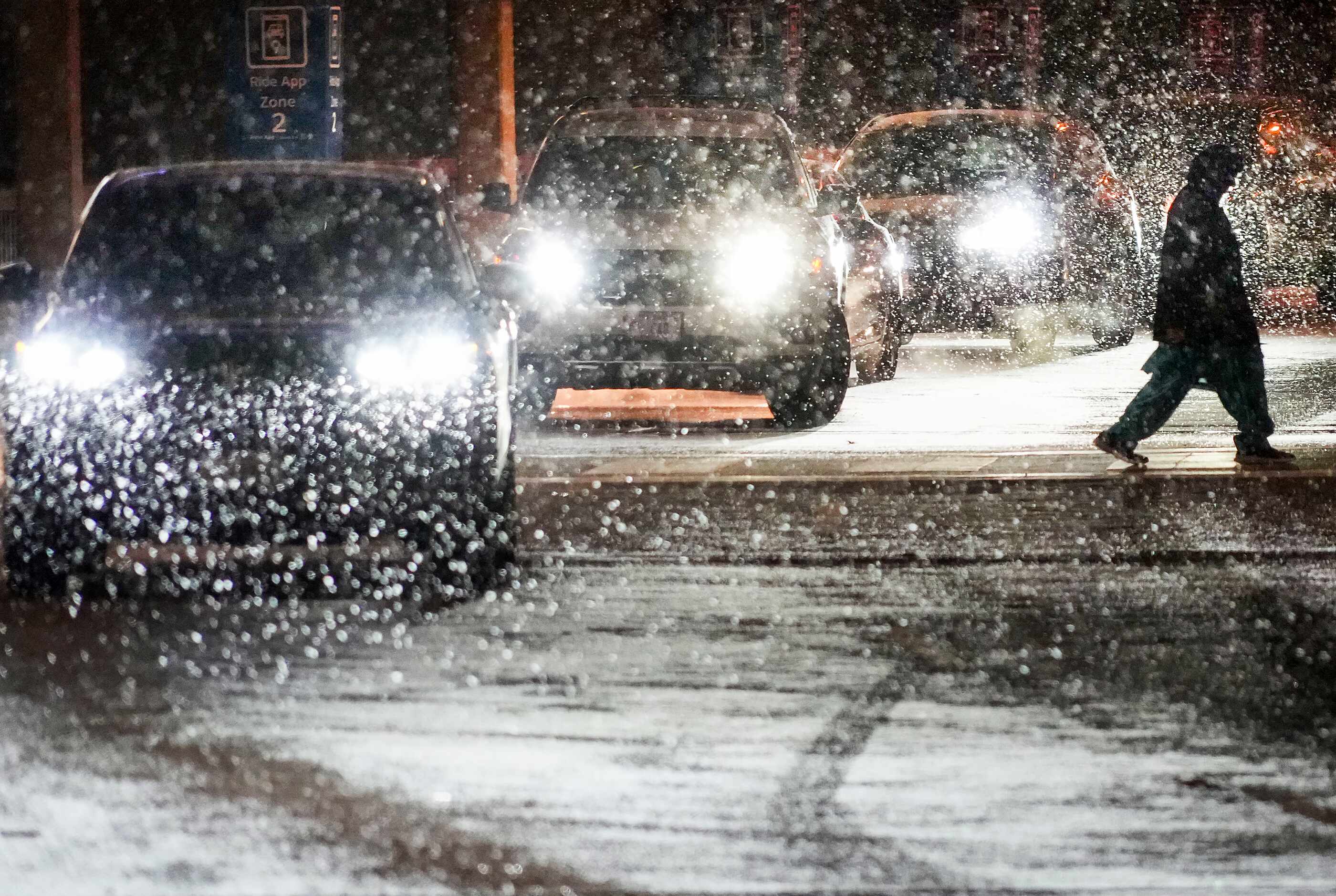 Snow falls over cars lined up for passenger pickup at  DFW International Airport in the...