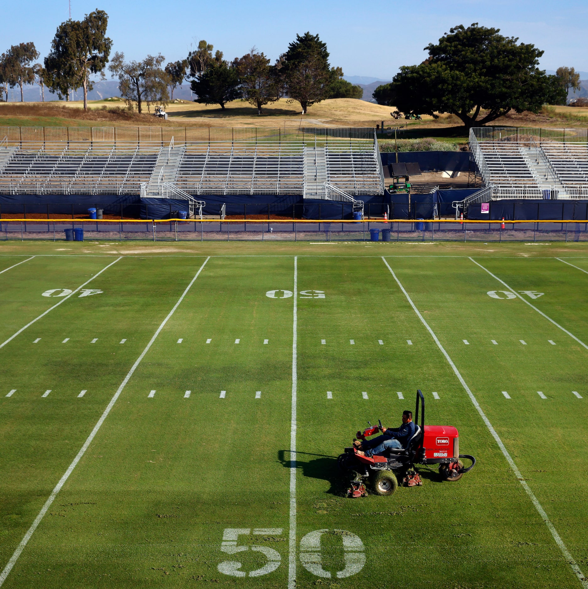 Grounds crewman Alberto Ortega cuts the grass fields in preparation for the Dallas Cowboys...