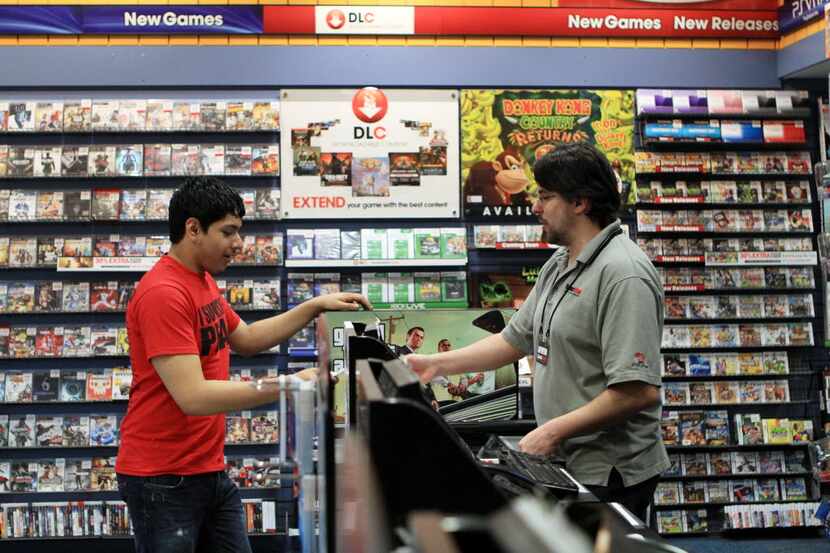 Jose Cisneros, 17, completes his transaction with manager David Green at the GameStop store...
