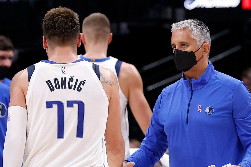 Dallas Mavericks assistant coach Igor Kokoskov (right) slaps hands with guard Luka Doncic...