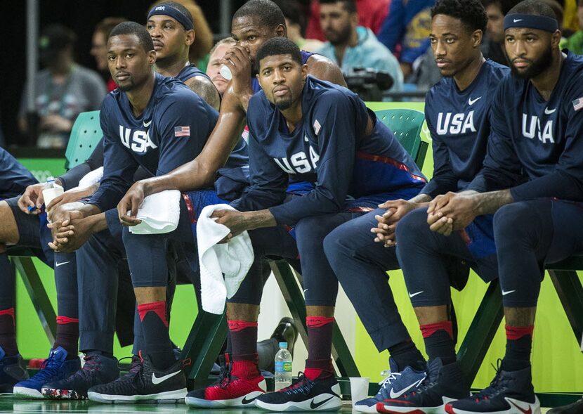 Harrison Barnes of the United States (far left) watches the game from the bench as they US...