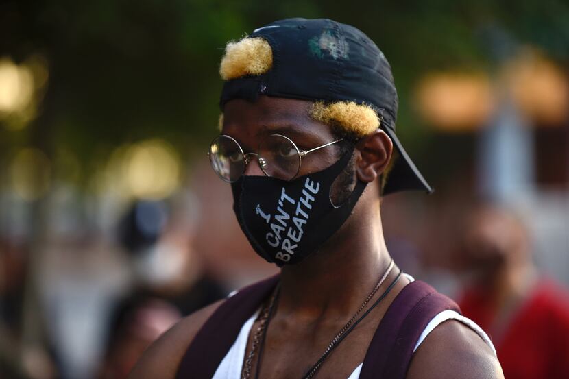 Le Lune, 23, of Arlington, listens to a speaker during a protest outside the Dallas Police...