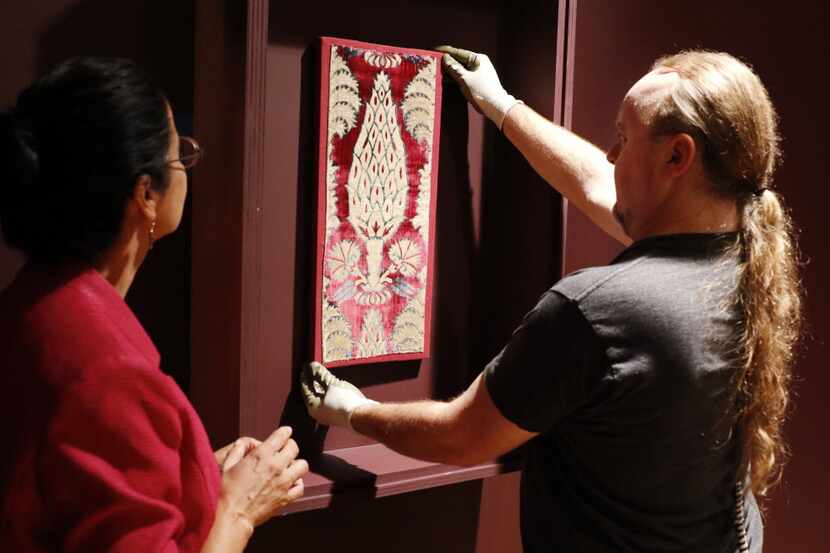 Doug Velek, of the Dallas Museum of Art, right, installs a textile from Asia, late 16th,...