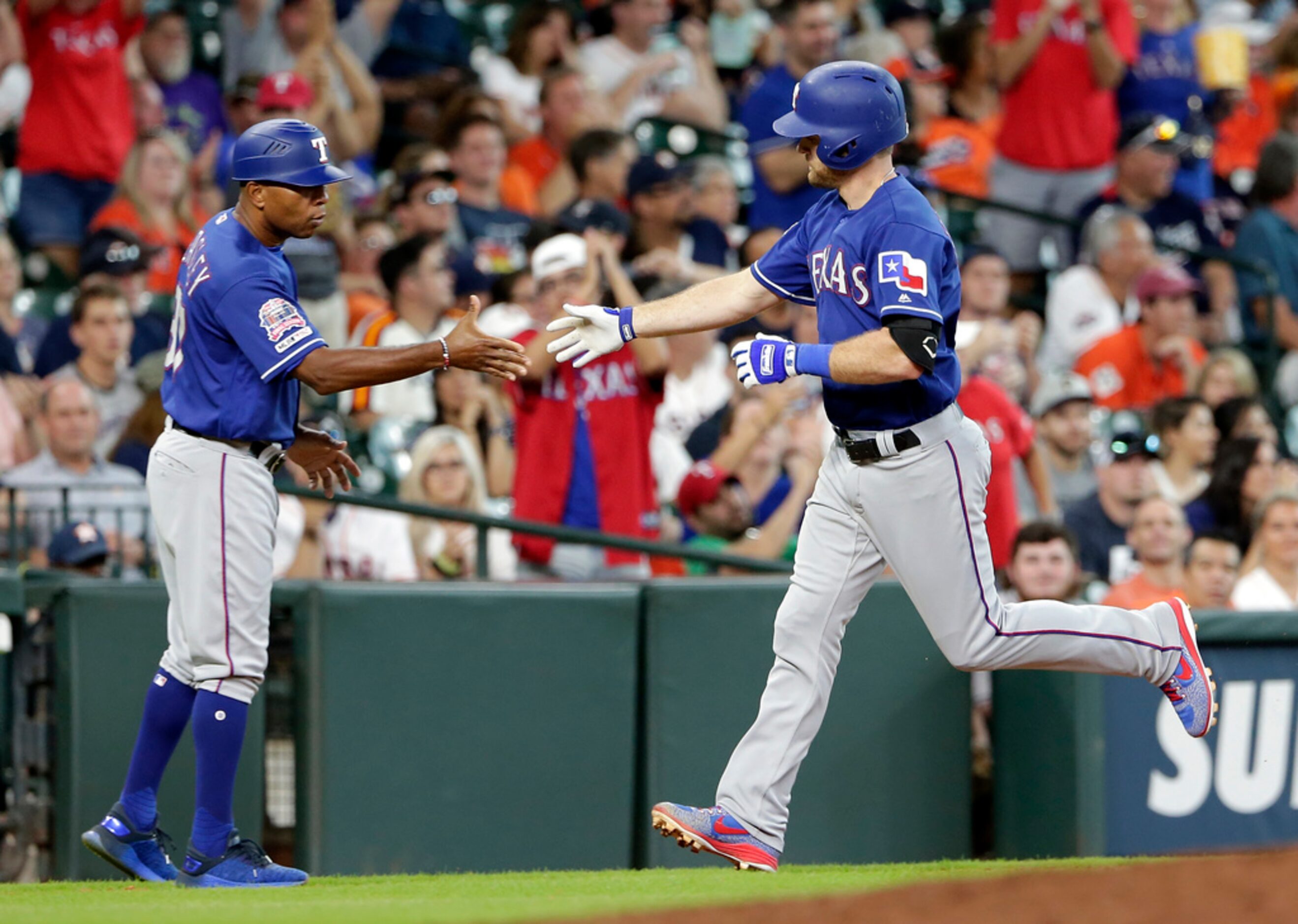 Texas Rangers third base coach Tony Beasley, left, congratulates, Logan Forsythe, right, as...