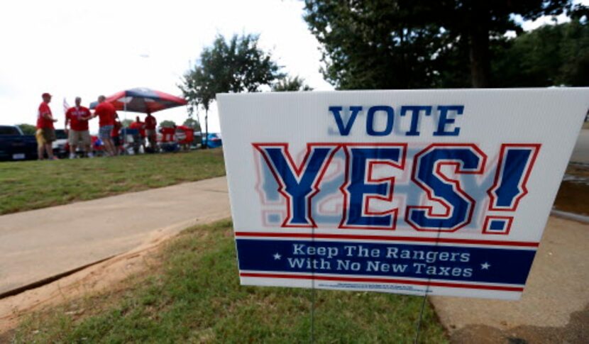 A sign of Vote Yes! Keep the Rangers is seen on Nolan Ryan Expressway as fans tailgate in...