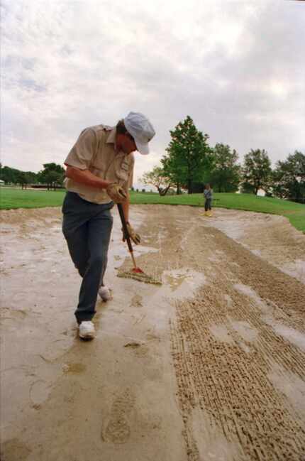Caption: 5/13/1994 -- Max Hess, left, and Saul Arroyo,  right, rake a wet and soggy fairway...