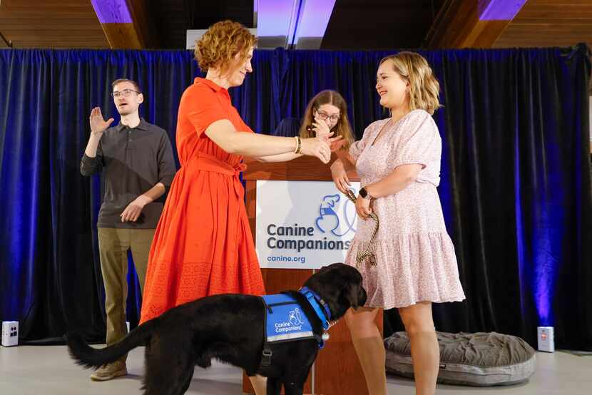 Puppy raiser Michaela Durisek (front left) reaches for congratulatory hug towards Lauren...