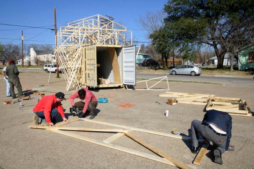 
Artists and organizers work on an ark made from a shipping container, old doors, shutters,...