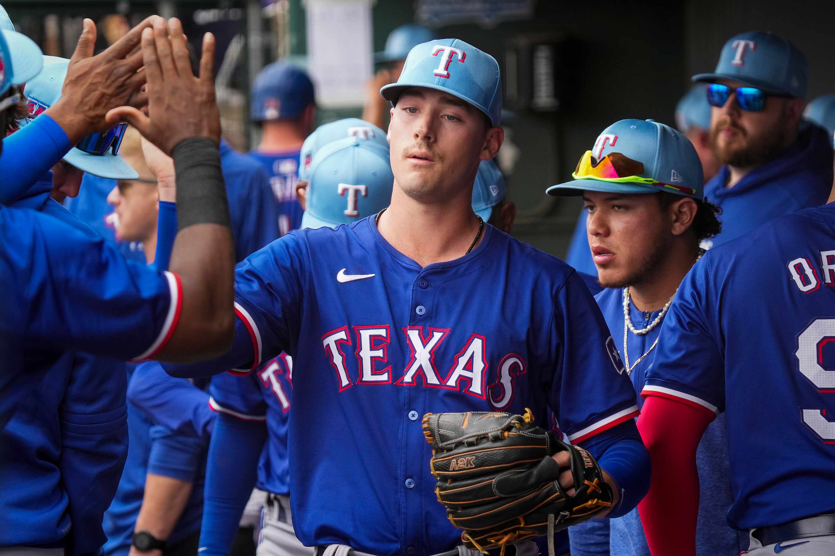 Texas Rangers pitcher Cole Winn high fives teammates as he leaves the game during the second...