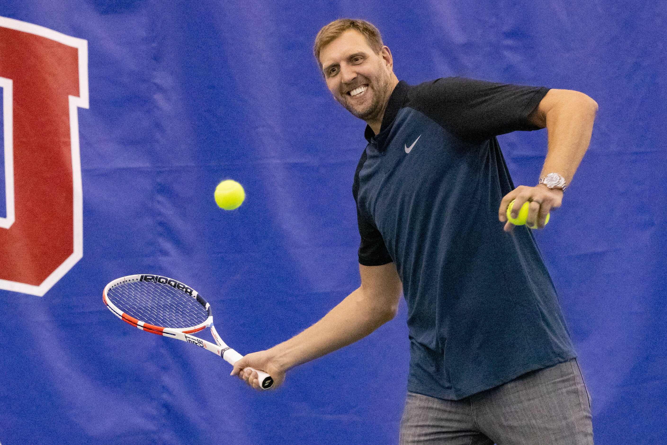 Dallas Mavericks star Dirk Nowitzki hits the tennis ball to John Isner, 15-Time ATP Tour...