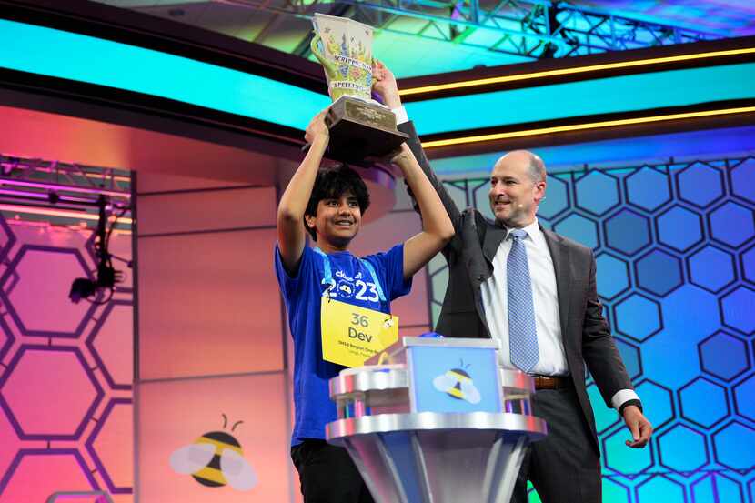 Dev Shah, 14, from Largo, Fla., lifts the trophy next to Scripps CEO Adam Symson after he...