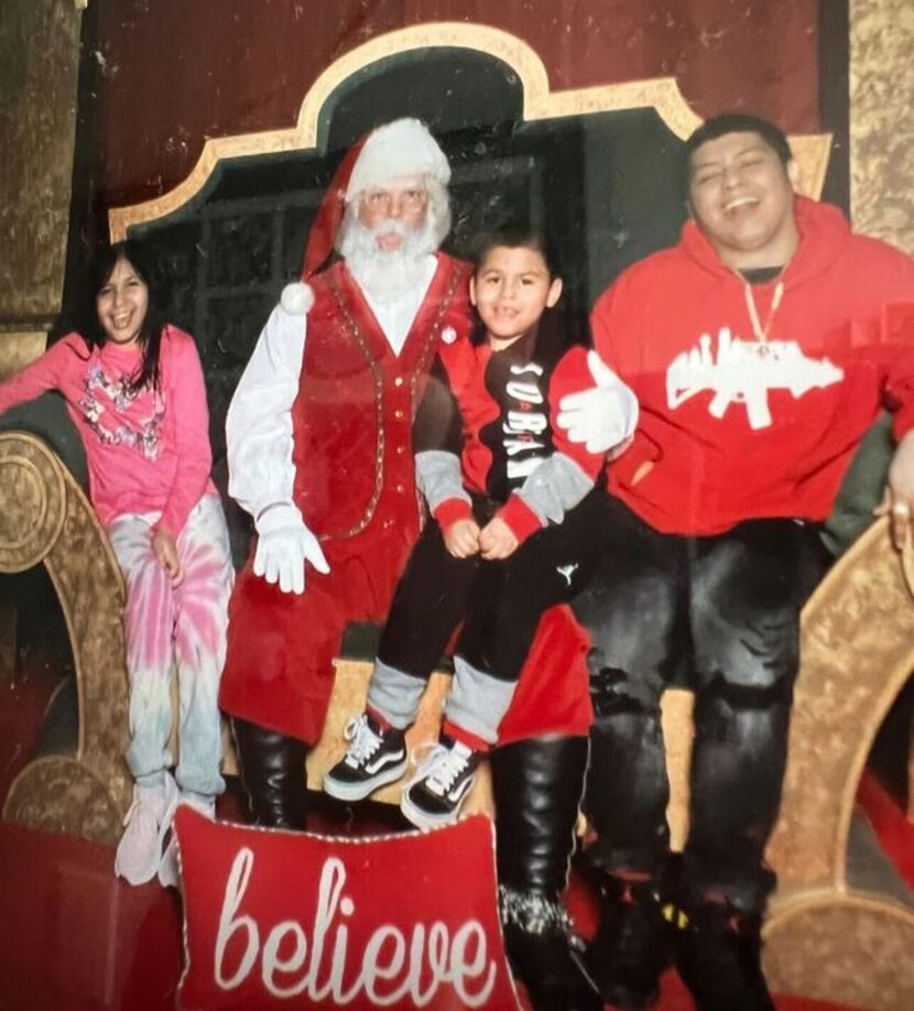 Carlos Roque (derecha), su hermano Jojo y su hermana Carly posan para una foto con Santa...