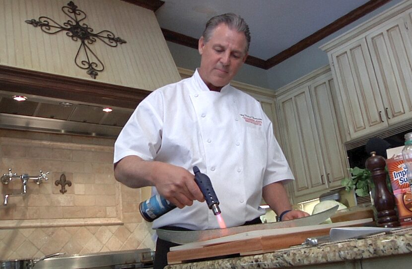 Dallas chef Richard Chamberlain gives Don Wall a lesson in searing fish using a small...