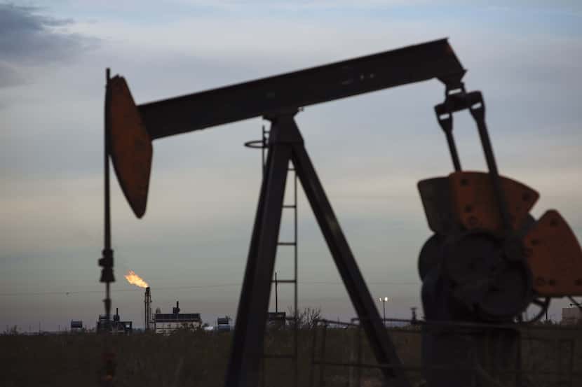 A gas flare burns past a pump jack in the Permian Basin, where Pioneer Natural Resources is...
