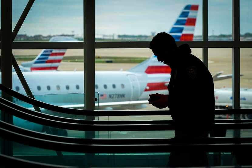 American Airlines are planes parked at their gates as passengers ride an escalator at DFW...