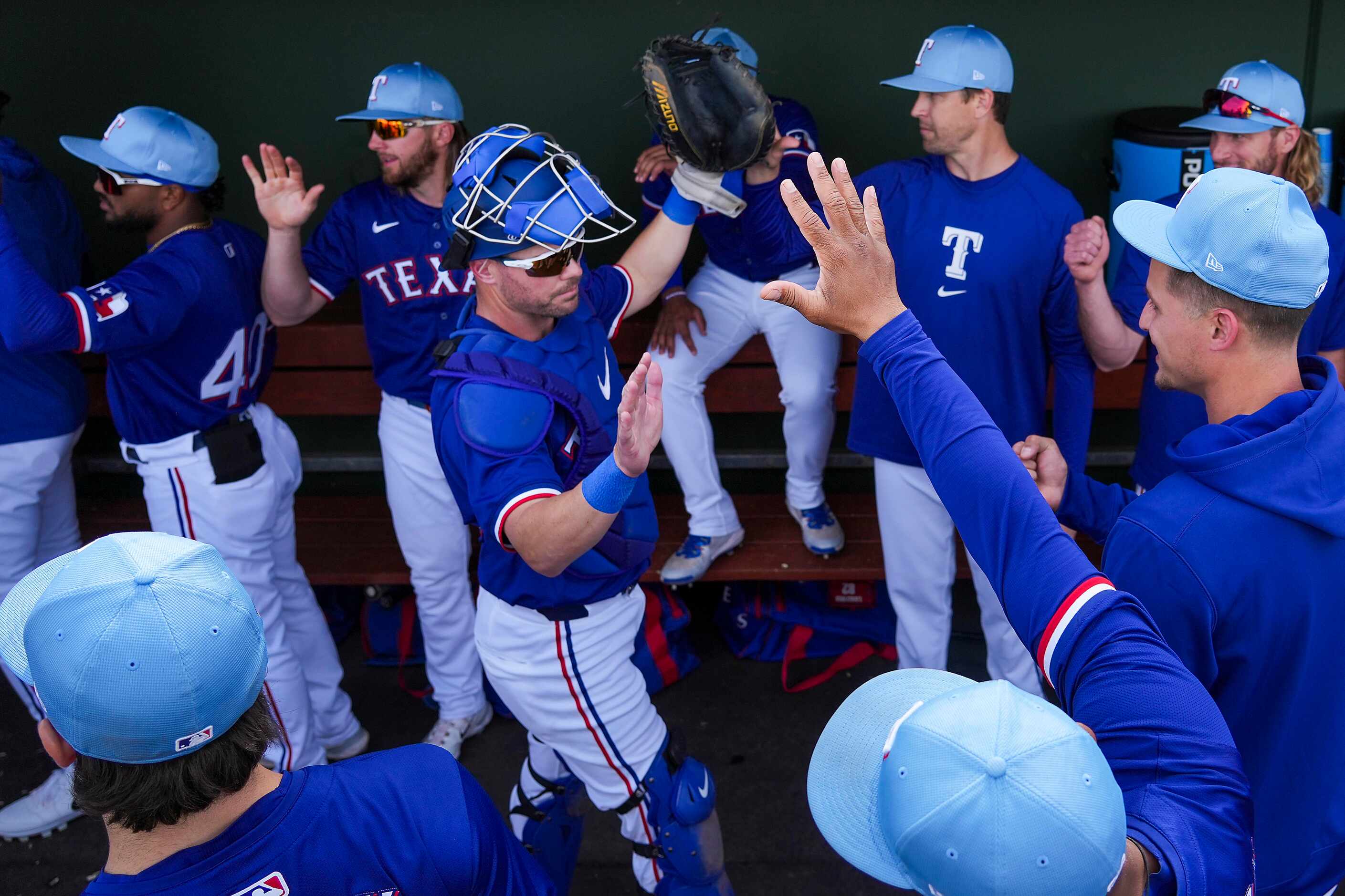 Texas Rangers catcher Andrew Knapp high fives teammates in the dugout before a spring...