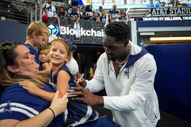 Dallas Cowboys defensive end DeMarcus Lawrence autographs the back of the dress of Penelope...