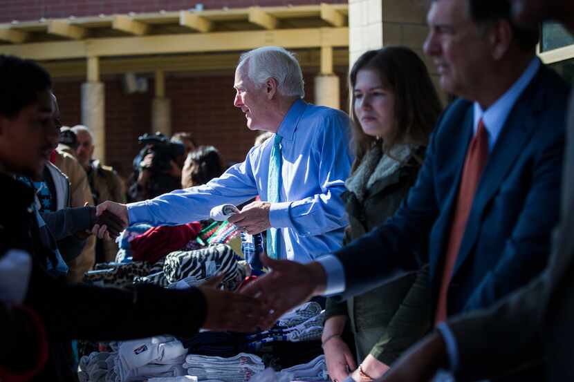 U.S. Senator John Cornyn, Dallas Mayor Mike Rawlings, right, and other volunteers hand out...
