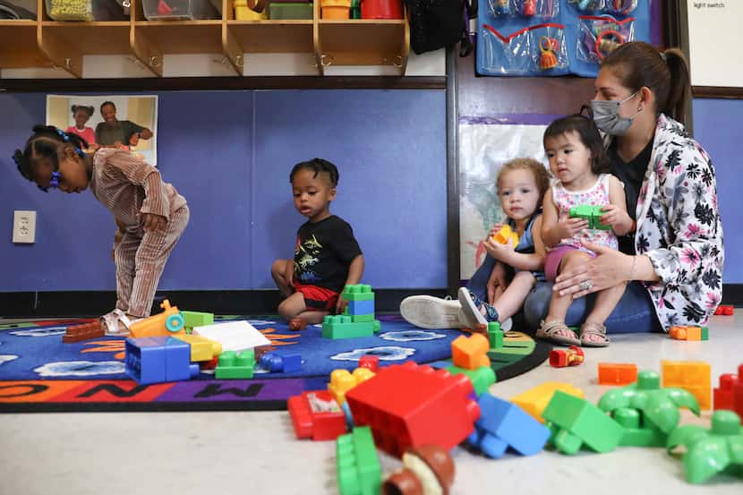 Teacher Erika Torres Rosado plays with 18-24 month olds Essence Payne (left to right), Ricky...
