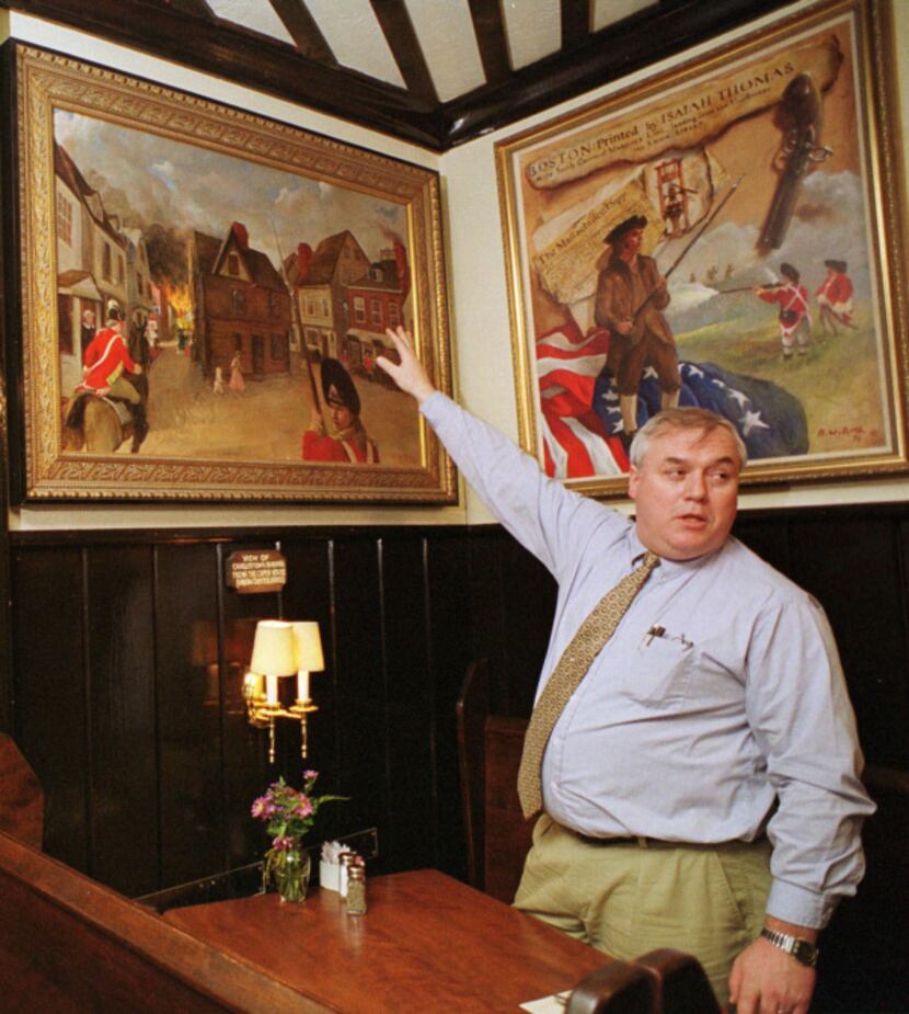 Jim Malinn, general manager of the Union Oyster House, gestures to paintings representing...