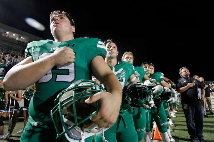 Members of the Southlake Carroll Dragons pause for the playing of the national anthem prior...