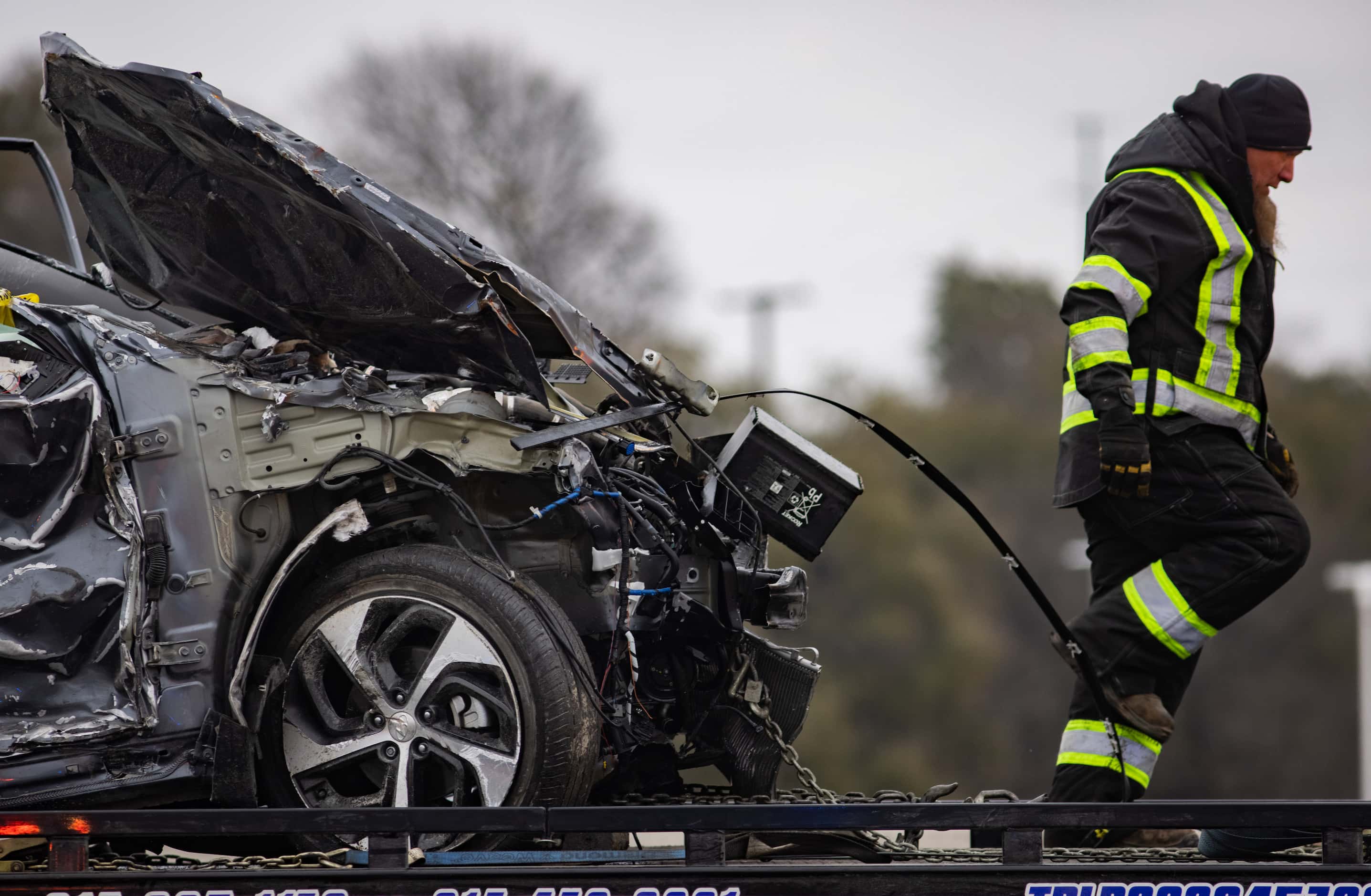 A crumbled car is towed as emergency crews work to clear the mass casualty pile-up on I-35W...
