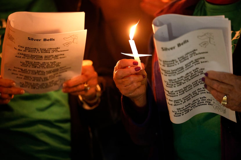 Members of the Legal Defense Fund Choir hold candles and sing Christmas songs during a...