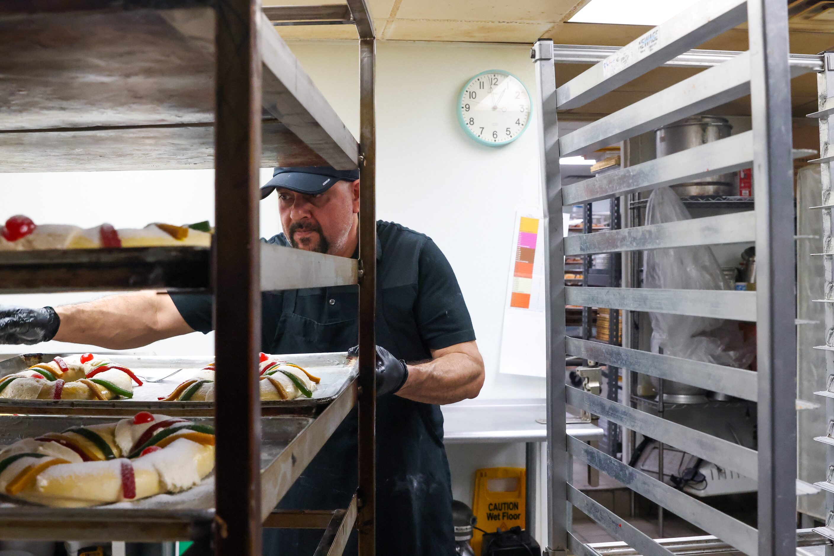 Baker Isaac Ramirez places prepared Rosca de Reyes on racks at Tango Bakery in Garland on...