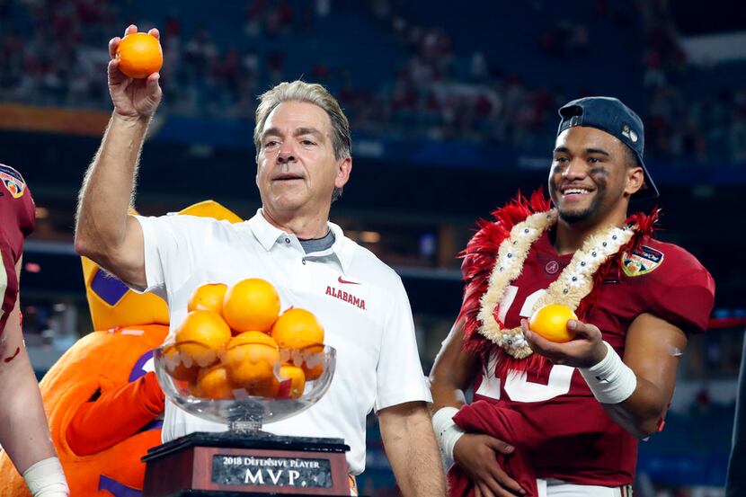 Alabama head coach Nick Saban and quarterback Tua Tagovailoa, throw oranges to the team...